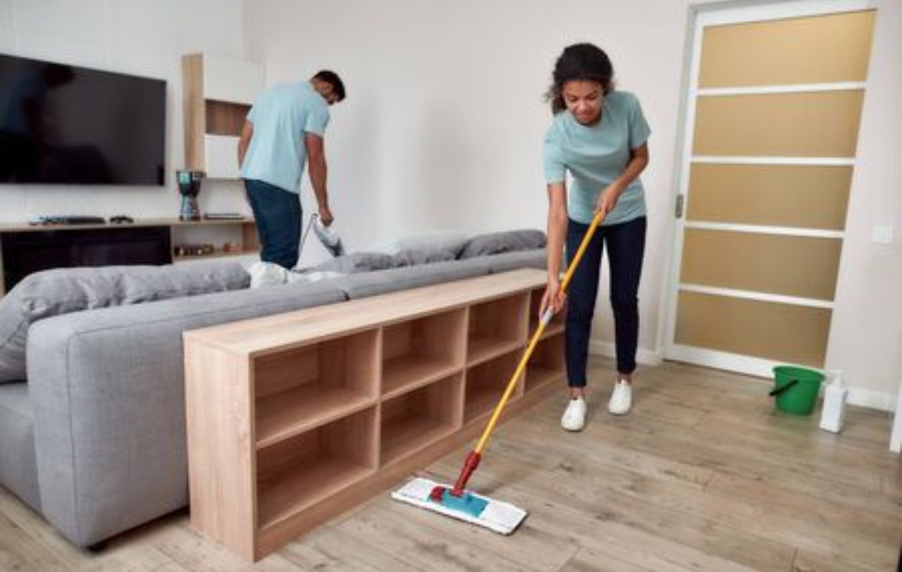 A woman and man cleaning the floor in a room.