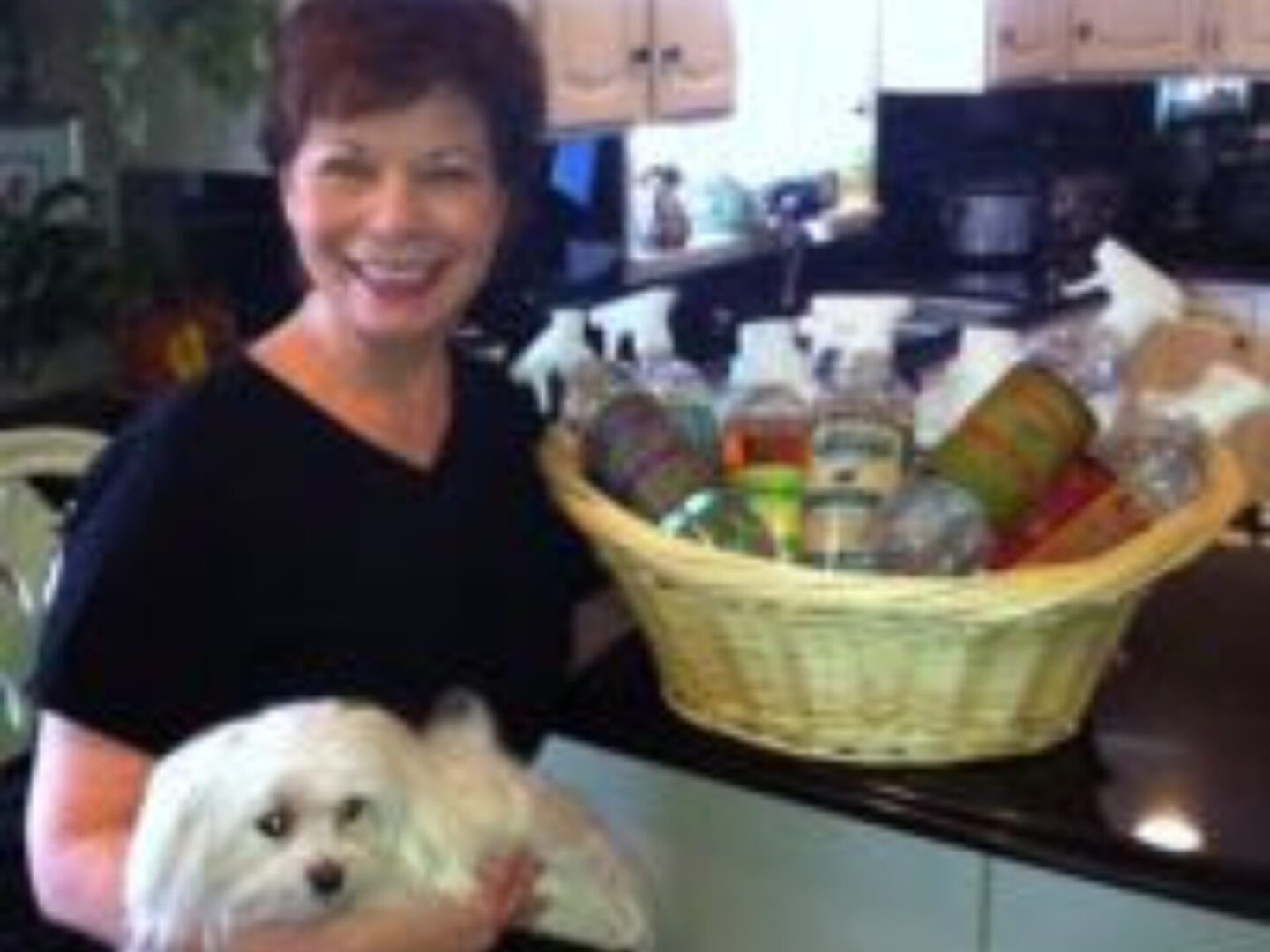 A woman holding a dog in her lap and smiling.